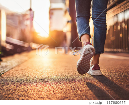スニーカーで歩く女性の足元（元気,若い,一人,足元,朝日,夕日,逆光） 117680635