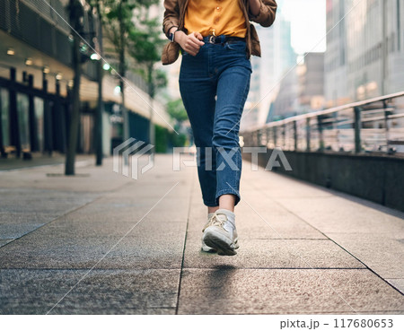 スニーカーで歩く女性の足元（元気,若い,一人,足元,朝日,夕日,逆光） 117680653