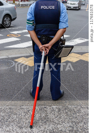 交差点に立つ警察官の後ろ姿 117681078