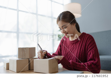 woman, online seller, efficiently manages customer orders and delivery through the e-commerce platform woman, online seller, efficiently manages customer orders and delivery through the e-commerce platform 117681952