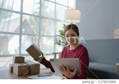 woman, online seller, using a tablet computer efficiently manages customer orders and delivery through the e-commerce platform 117681960