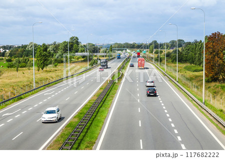 Aerial view of a highway with multiple lanes, showcasing the flow of traffic, including cars and trucks. highlighting the movement and organization of vehicles on a major roadway Aerial view of a highway with multiple lanes, showcasing the flow of traffic, including cars and trucks. highlighting the movement and organization of vehicles on a major roadway 117682222