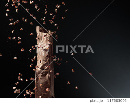Large piece of dark chocolate and falling chocolate crumbs. Large piece of dark chocolate and falling chocolate crumbs. 117683093