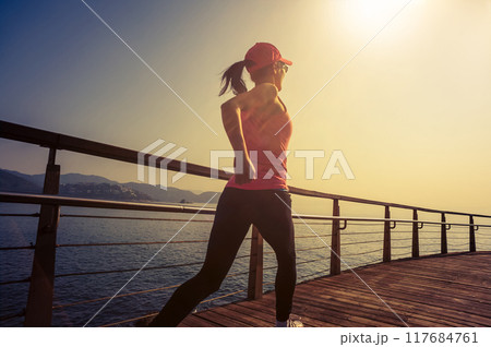 Healthy lifestyle sports woman running on wooden boardwalk seaside Healthy lifestyle sports woman running on wooden boardwalk seaside 117684761