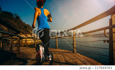 Healthy lifestyle sports woman running on wooden boardwalk seaside 117684763