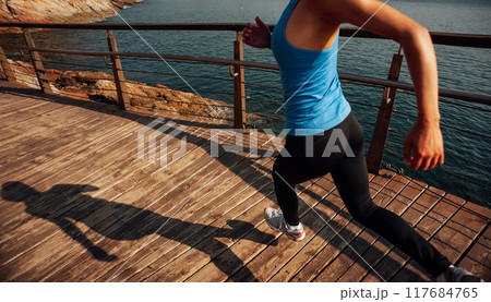 Healthy lifestyle sports woman running on wooden boardwalk seaside Healthy lifestyle sports woman running on wooden boardwalk seaside 117684765
