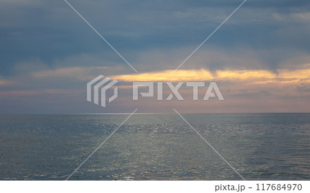 Seascape. Waves and surf. Sunset and dawn at sea. Calm on the ocean. Beautiful sky and clouds illuminated by the sun. Natural background. Summer time. 117684970
