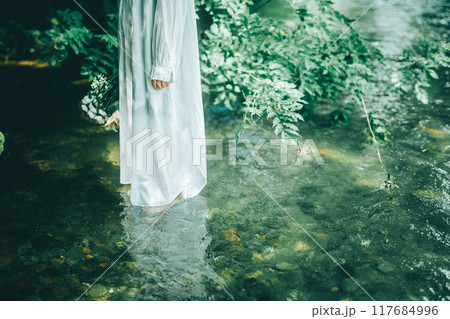 白いワンピースで夏の川に入っている女性の足元 117684996