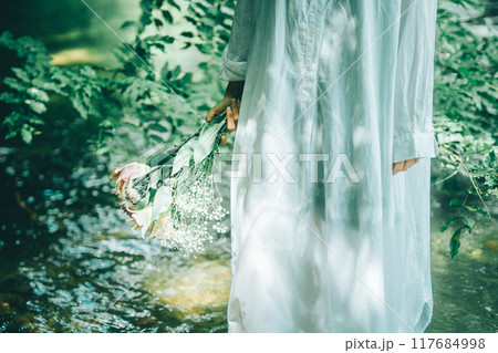 夏の川で、白いワンピースに木漏れ日が映る様子 117684998