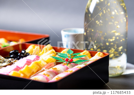 盛り付けられたお節料理と金箔入りの日本酒 盛り付けられたお節料理と金箔入りの日本酒 117685433