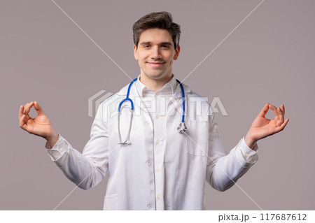 Calm doctor man relaxing, meditating, refuses stress. Hospital worker breathes 117687612