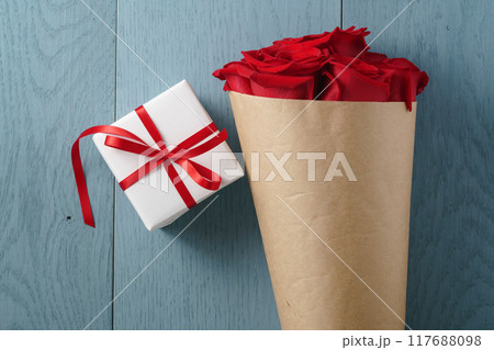 red roses bouquet on blue wood table with gift box top view 117688098