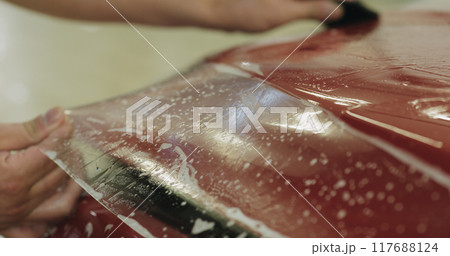 professional applying protective film to the red car 117688124