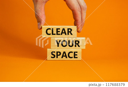 Clear your space symbol. Wooden blocks with words 'Clear your space'. Beautiful orange background, businessman hand. Business, clear your space concept, copy space. Clear your space symbol. Wooden blocks with words 'Clear your space'. Beautiful orange background, businessman hand. Business, clear your space concept, copy space. 117688379