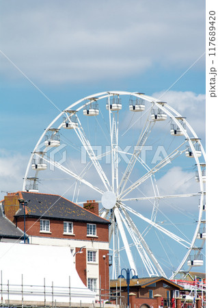遊園地の旧式な白い観覧車と赤煉瓦の建物　南ウェールズの郊外にて 117689420