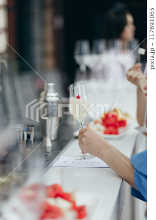 A girl takes a glass of sparkling champagne at a bar A girl takes a glass of sparkling champagne at a bar 117691065