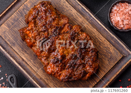 Fresh juicy delicious beef steak on a dark background Fresh juicy delicious beef steak on a dark background 117691260