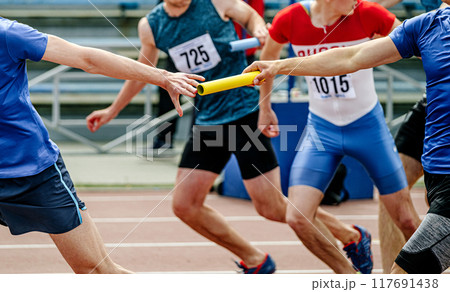 passing baton to men team athletes in athletics relay race 117691438