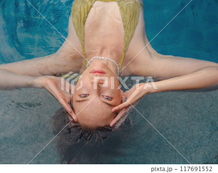 Vacation lifestyle scene of young woman sitting in swimming pool Vacation lifestyle scene of young woman sitting in swimming pool 117691552