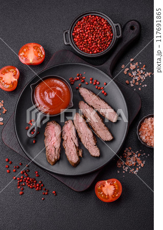 Fresh juicy delicious beef steak on a dark background Fresh juicy delicious beef steak on a dark background 117691865