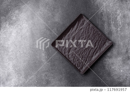 Empty ceramic plate on a dark textured background Empty ceramic plate on a dark textured background 117691957