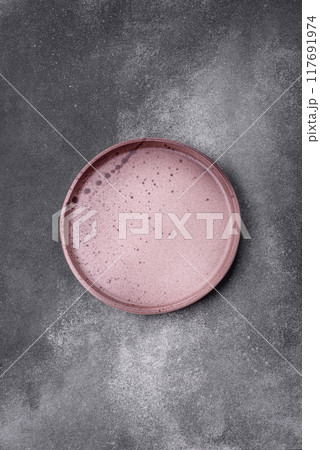 Empty ceramic plate on a dark textured background Empty ceramic plate on a dark textured background 117691974
