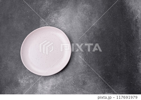 Empty ceramic plate on a dark textured background 117691979