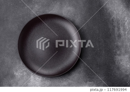 Empty ceramic plate on a dark textured background Empty ceramic plate on a dark textured background 117691994