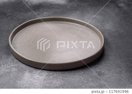 Empty ceramic plate on a dark textured background Empty ceramic plate on a dark textured background 117691996