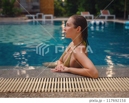 Vacation lifestyle scene of young woman sitting in swimming pool Vacation lifestyle scene of young woman sitting in swimming pool 117692158