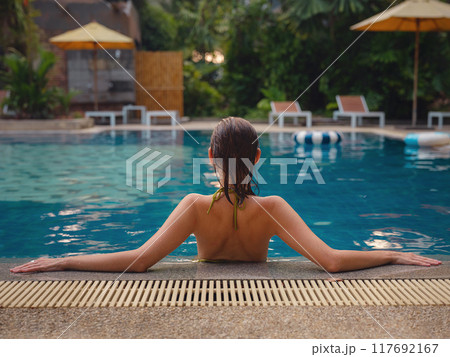 Vacation lifestyle scene of young woman sitting in swimming pool 117692167