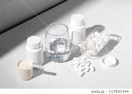 Food supplement concept. Capsules of probiotics, vitamins, white pills and a scoop of protein collagen powder. Food supplement concept. Capsules of probiotics, vitamins, white pills and a scoop of protein collagen powder. 117692444