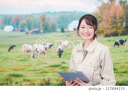 牧場で働く作業服姿の若い女性 117694153