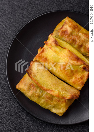 Homemade fried pancakes with filling on a ceramic plate Homemade fried pancakes with filling on a ceramic plate 117694840