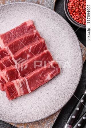Fresh raw beef cut into slices with salt, spices Fresh raw beef cut into slices with salt, spices 117694902