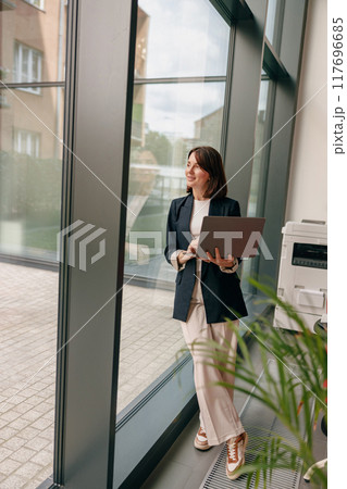 A modern businesswoman works remotely in her office using a laptop for efficiency and productivity A modern businesswoman works remotely in her office using a laptop for efficiency and productivity 117696685