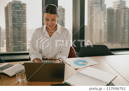 A Professional Woman is Working Efficiently on a Laptop in a Contemporary Office Space 117696762