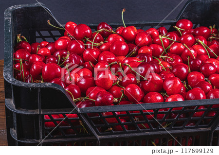 ripe cherries in a plastic box on the table top view 117699129