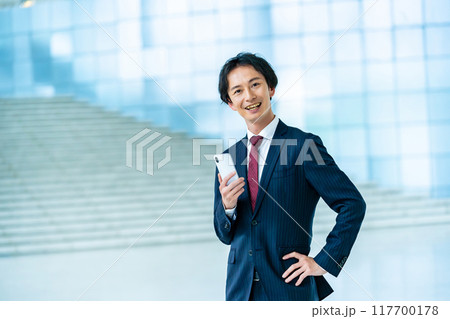 スマホを持ったビジネスマン　スーツを着た男性ビジネスマン 117700178