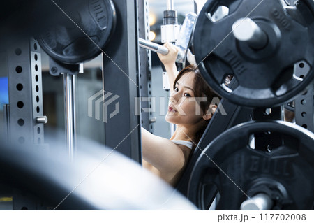 スポーツジムでトレーニングする若い女性 スポーツジムでトレーニングする若い女性 117702008