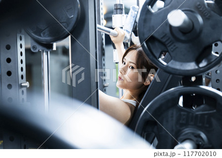 スポーツジムでトレーニングする若い女性 117702010