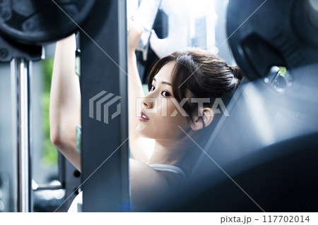 スポーツジムでトレーニングする若い女性 117702014