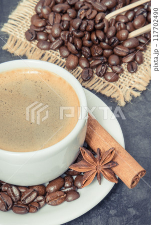 Coffee in cup and roasted dark coffee beans with anise and cinnamon Coffee in cup and roasted dark coffee beans with anise and cinnamon 117702490
