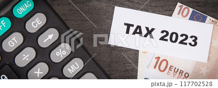 Calculator, inscription tax 2023 and euro banknotes. Time of calculating, return or tax payment 117702528