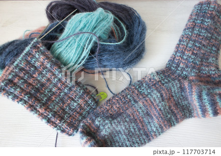 Colourful yarn ball with knitted sock and knitting needles. Alpaca and wool threads with beautiful knitting pattern. Woven crochet close up. Knitting hobby. Knitwear concept. Needlework background.  117703714