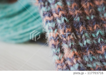 Colourful yarn ball with knitted sock and knitting needles. Alpaca and wool threads with beautiful knitting pattern. Woven crochet close up. Knitting hobby. Knitwear concept. Needlework background.  117703716