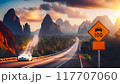 A high-speed highway in a picturesque mountainous area. There is a road sign on the side of the road warning about the speed limit 117707060