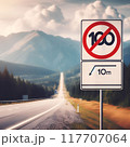 A high-speed highway in a picturesque mountainous area. There is a road sign on the side of the road warning about the speed limit 117707064