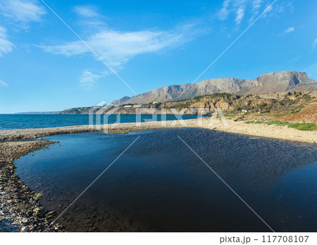 Small river flows into the sea on pebble beach 117708107