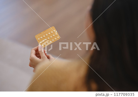 A woman is holding a pill in her hand 117709335